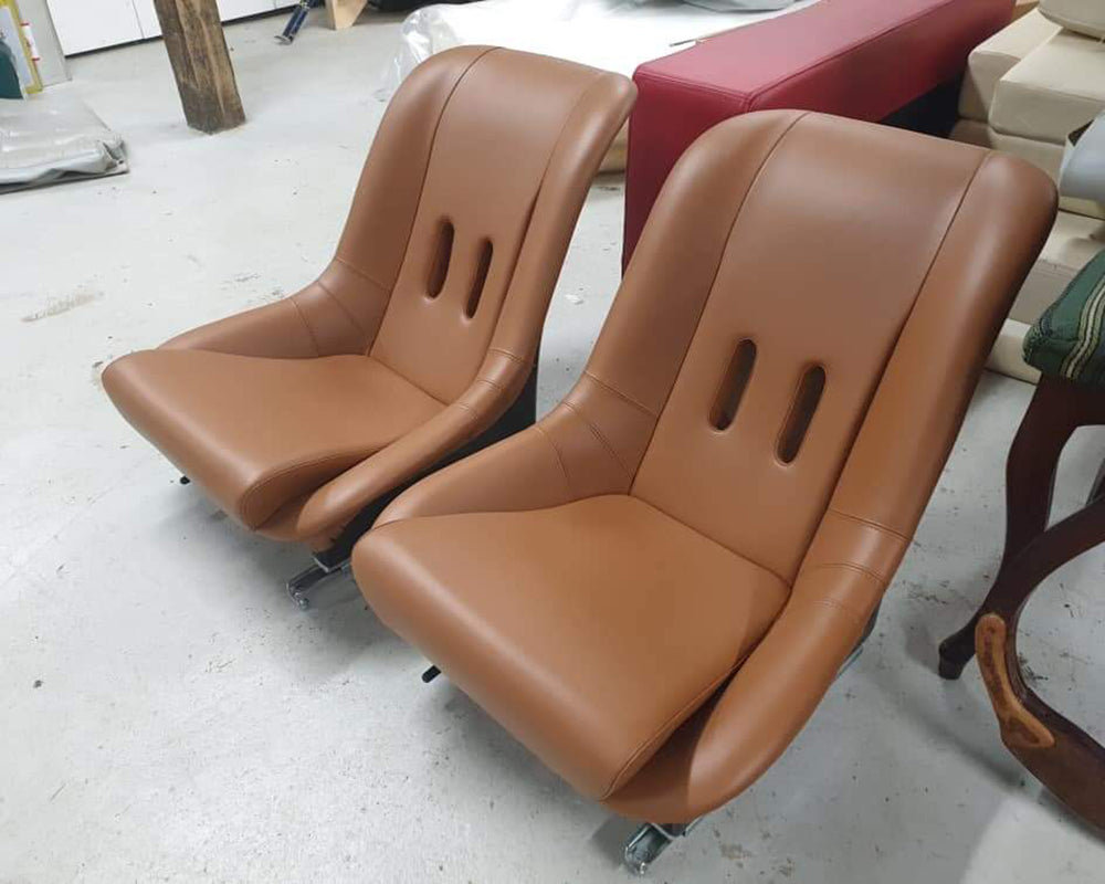 Two brown leather chairs on wheels in a workshop setting