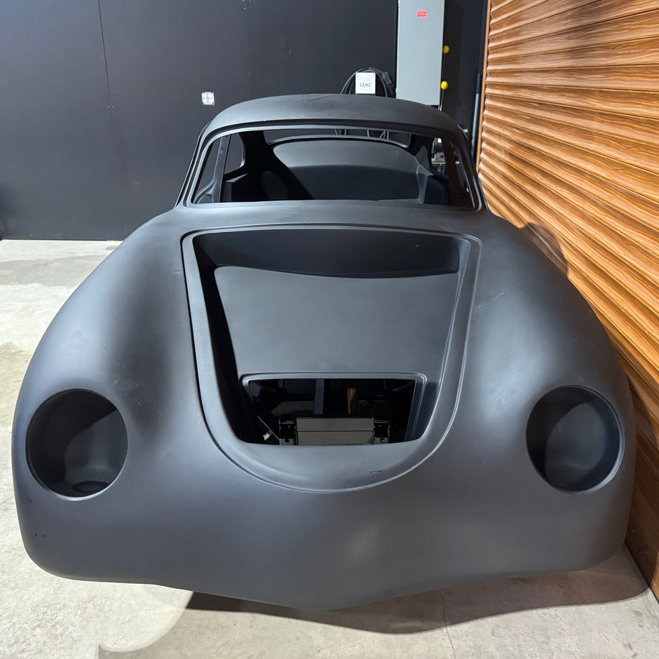 Gray car body against a wooden wall