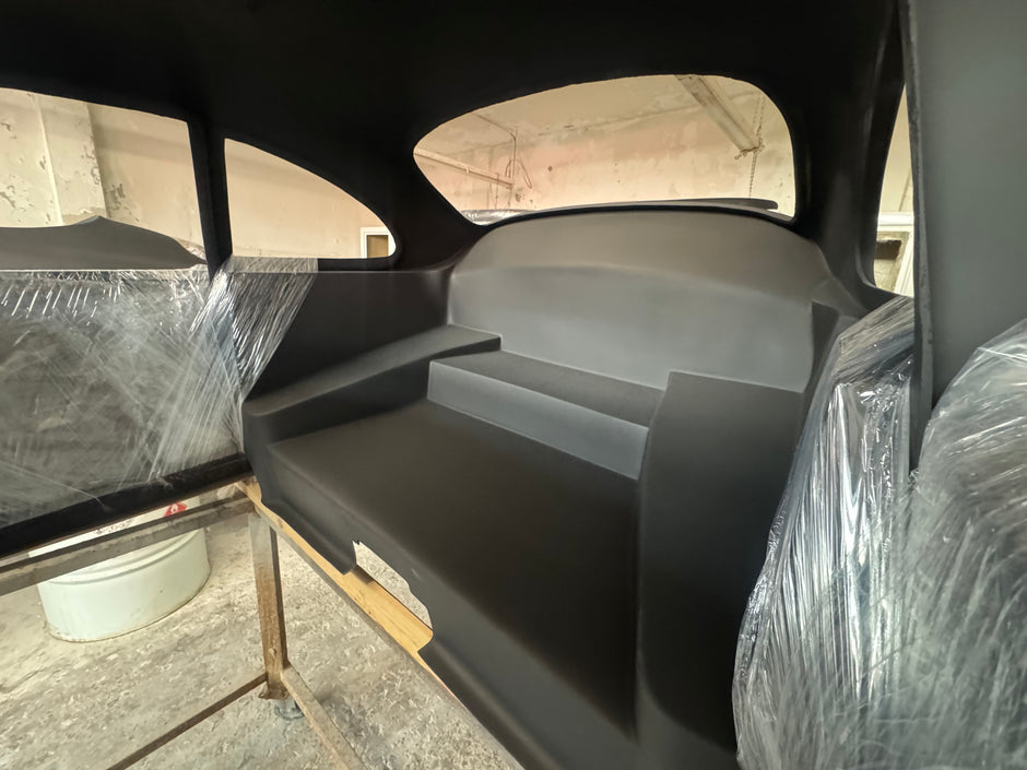 Car interior with plastic wrap on seats and windows, showing a repair or restoration process.
