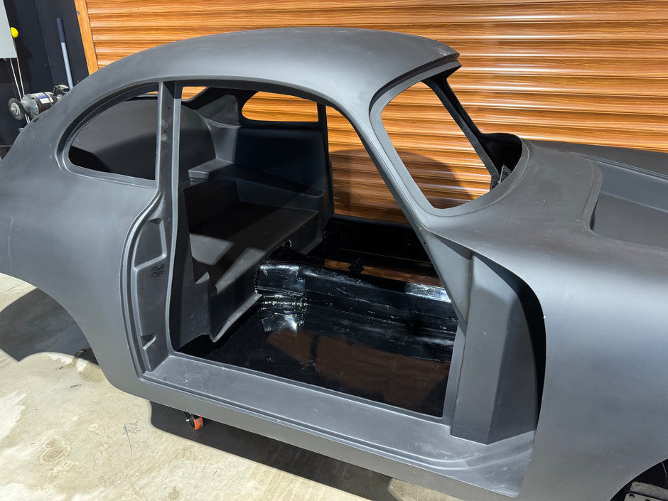 Car body shell without doors and windows on a concrete floor.